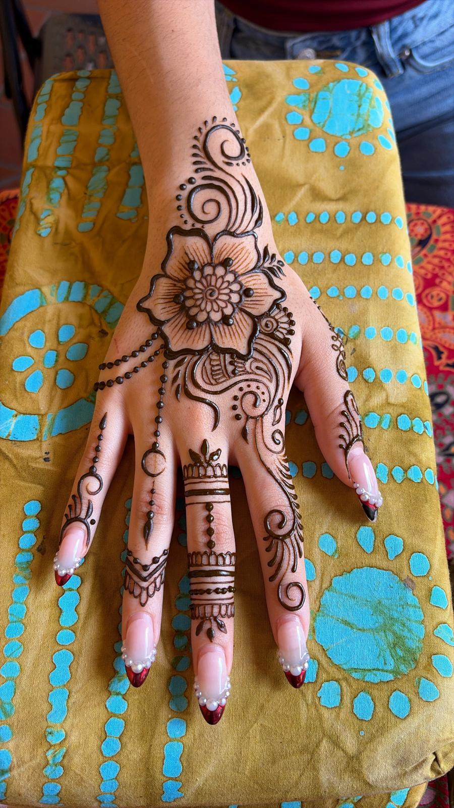 Hand with intricate henna design on a yellow fabric background