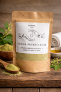 Henna package with label on a wooden surface with henna powder and leaves.