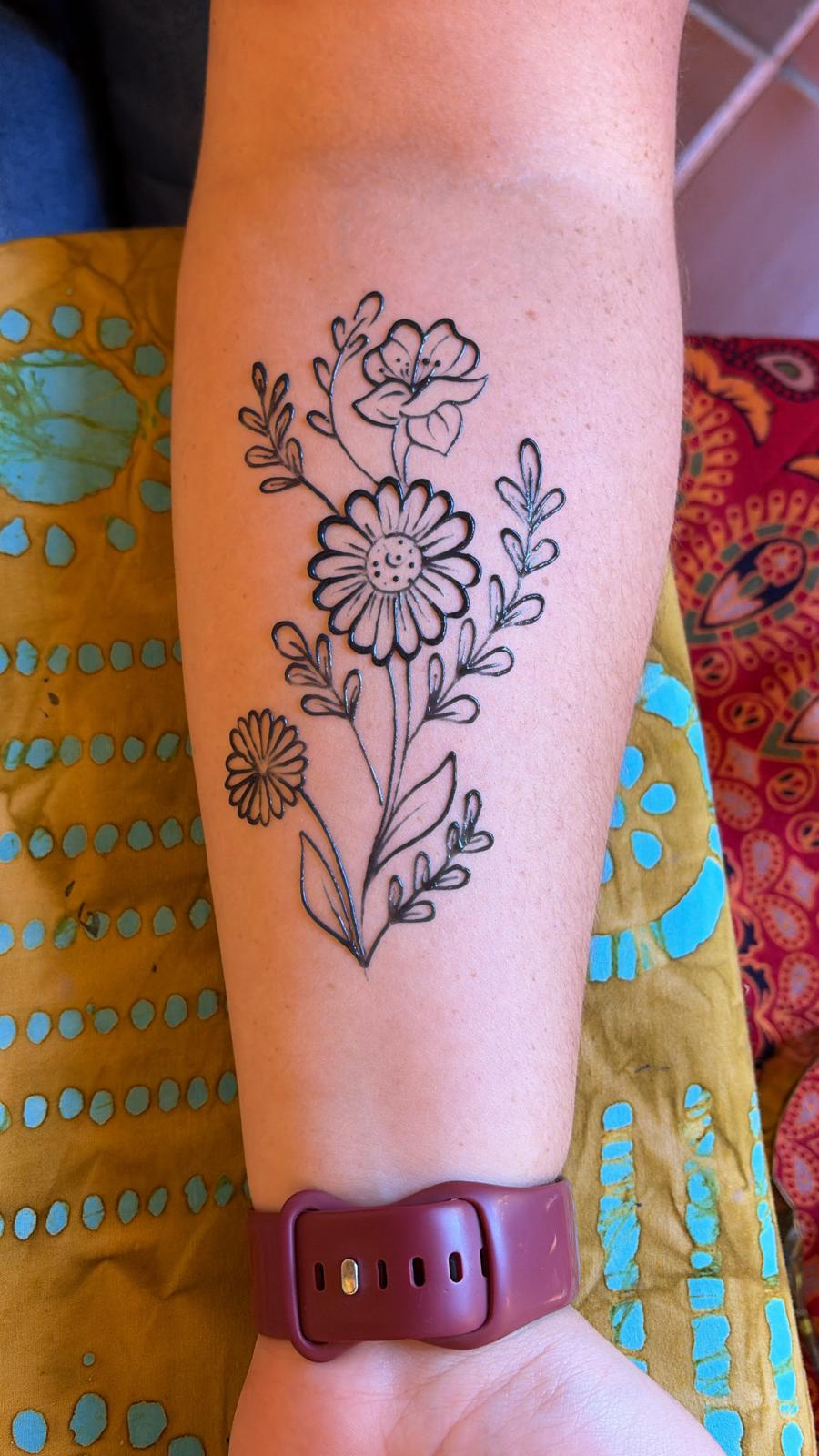 Floral jagua tattoo on a person's arm with a colorful background