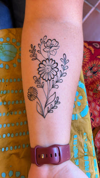 Floral jagua tattoo on a person's arm with a colorful background