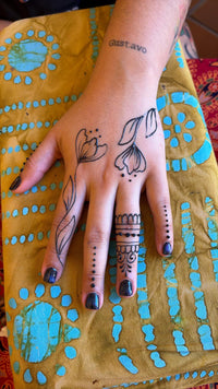 Hand with floral jagua designs on a yellow fabric background