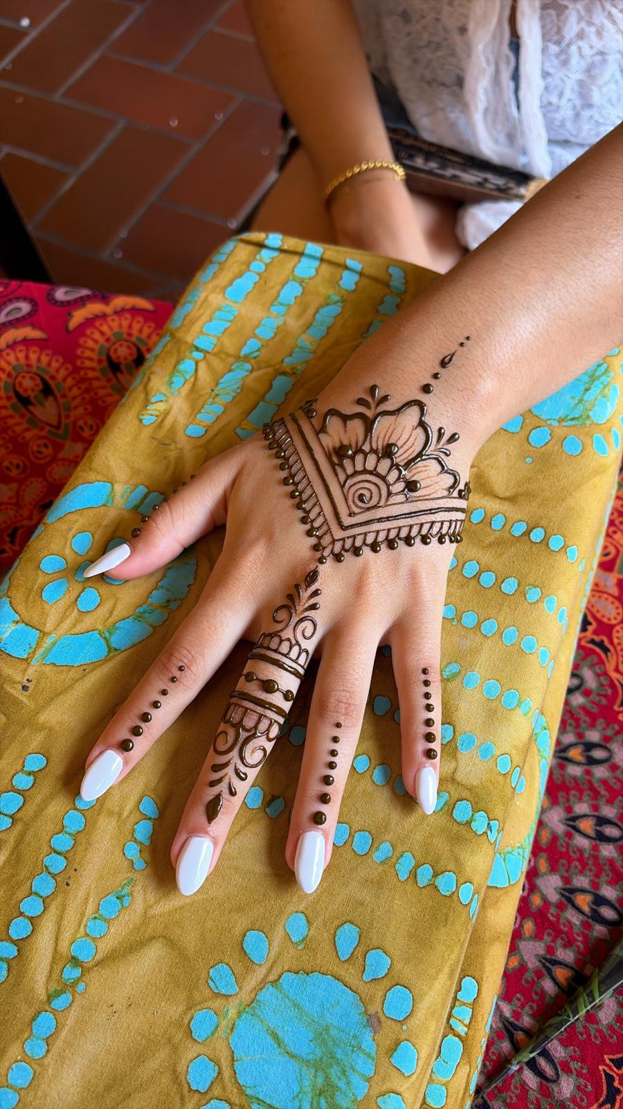 Hand with intricate henna design on a yellow fabric background