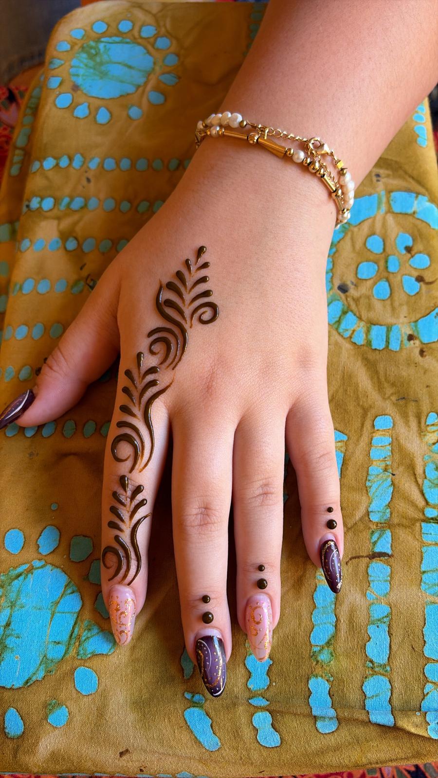 Hand with henna design on a colorful fabric background